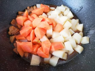 咖喱鸡肉土豆,下入胡萝卜和土豆翻炒均匀。
