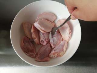 香酥炸鸡翅,把鸡翅沥干水分，为了方便入味，可以用叉子在鸡翅上戳一戳。在鸡翅反面划二刀，方便更快腌渍入味。