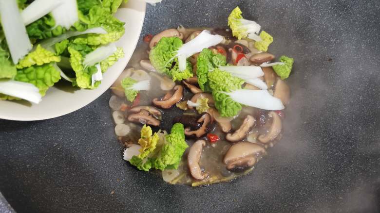 青菜炒香菇,倒入清洗好的青菜。