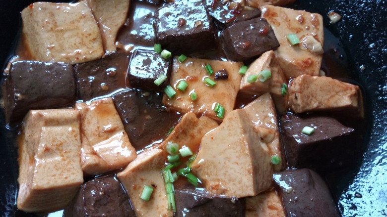 鸭血烧豆腐,煮至鸭血豆腐入味上色即可出锅，撒上大蒜叶
