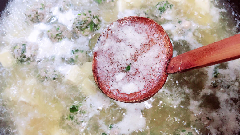 豆腐丸子汤,用勺子盛出表层沫子。