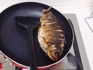 香煎鲫鱼,鱼的两边肉比较厚不好煎，可以把平底锅倾斜一点来煎。煎好后把鱼捞起来。