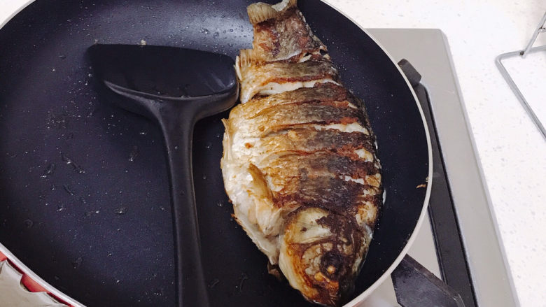 香煎鲫鱼,鱼的两边肉比较厚不好煎，可以把平底锅倾斜一点来煎。煎好后把鱼捞起来。