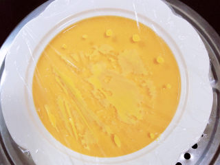 南瓜鸡蛋羹,将蒸碗盖上一层保鲜膜，用牙签扎一些洞眼。放入蒸锅中，大火蒸12分钟。