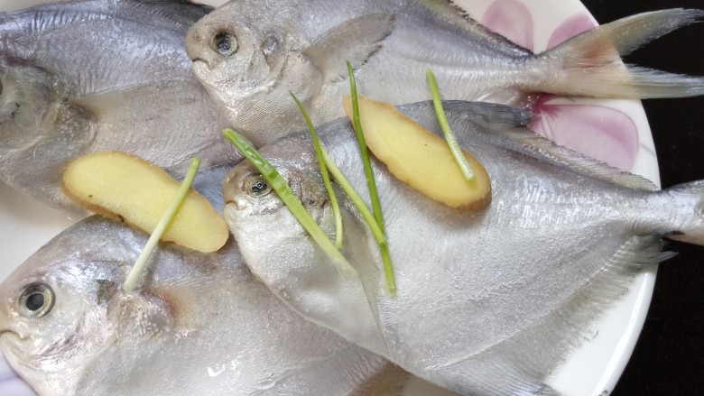 清蒸白鲳鱼,放入盐、生姜和葱段将鱼腌制一会
