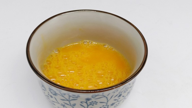 鸡蛋炒年糕,鸡蛋磕入碗里、加2克盐用筷子打散。