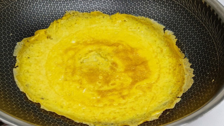 鸡蛋炒年糕,锅里放油，开小火倒入鸡蛋液，转圈把鸡蛋液摊成饼状，等鸡蛋液凝固开中火，记得另外一面也翻过来煎一下。