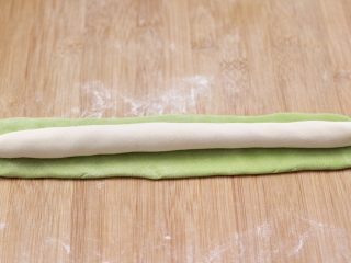 韭菜虾仁翡翠饺子,把面团揉匀，白色的搓成长条，绿色的擀成面皮，白色的放到上面，用绿色的面皮包裹起来搓成长条。