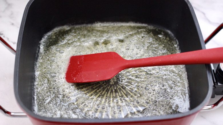 芝麻核桃糖,把融化好的黄油，均匀地摇匀整个锅底。
