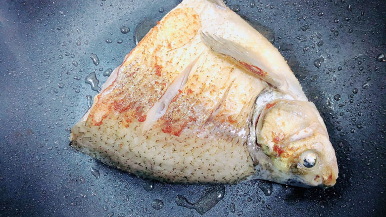 砂锅鱼头煲,将鱼头翻面，继续煎至另一面也为金黄色。取出鱼头。