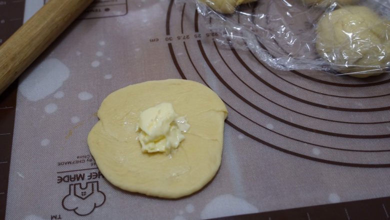 摩卡咖啡面包,取出后分成8等份，揉成圆形，盖上保鲜膜松弛15分钟后，把面团擀平，放入少许黄油。