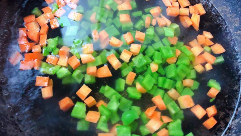 蔬菜虾仁粥,锅中烧开水放入切好的青椒粒和胡萝卜粒焯水时间不要过长刚刚变色漂浮起来即可