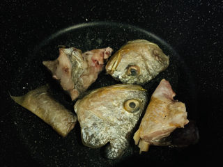 砂锅鱼头煲,将鱼头放锅里，用小火煎；