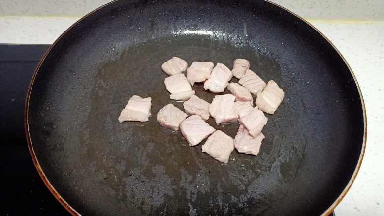 猪肉炒胡萝卜、蒜苔,锅中放入适量油，油热后放入猪肉炒至变色
