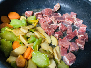 杏鲍菇炒牛肉,把杏鲍菇、胡萝卜、芥菜拨到锅边放入牛肉粒