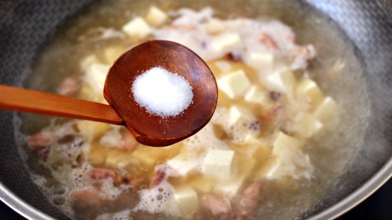 金针菇豆腐鱿鱼煲,锅中倒入适量的清水烧开后，放入焯水的豆腐，根据个人口味加入适量的盐调味。