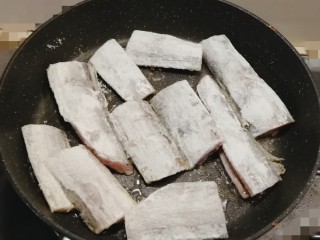 红烧糖醋带鱼,将裹了面粉的鱼块放入锅中煎制