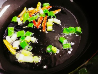 腊肠炒面,锅中倒油，油热后放入葱花和小米椒