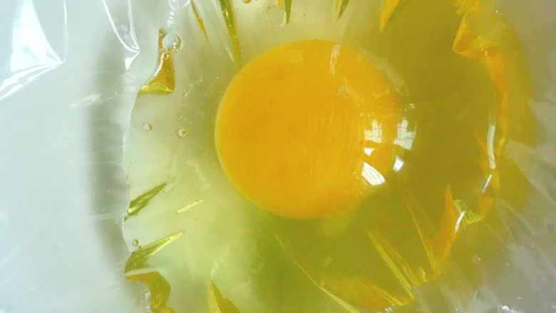 糖水鸡蛋,将鸡蛋打入隔了保鲜膜的碗中。