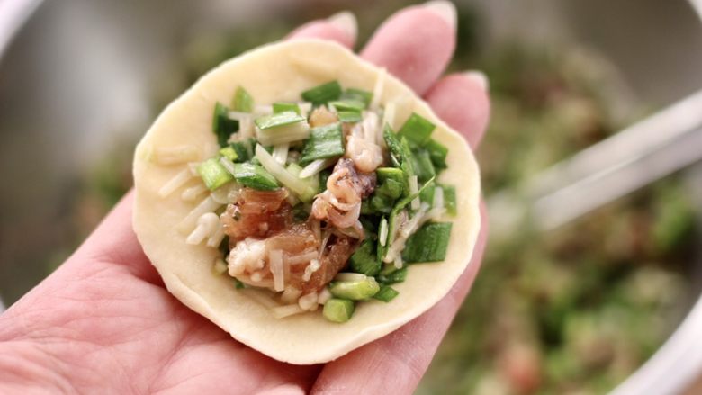 肉丁金针菇鱿鱼饺子,面皮上放入适量的馅料。