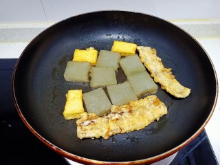 皮渣炒豆腐、带鱼、蒜苔、胡萝卜,煎至两面金黄，放入豆腐、带鱼