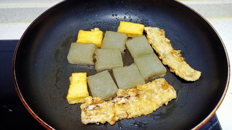 皮渣炒豆腐、带鱼、蒜苔、胡萝卜,煎至两面金黄，放入豆腐、带鱼