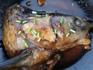 麻辣鱼头,小火炖煮至入味上色即可，撒上葱花关火。