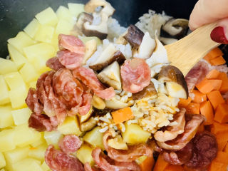 香菇腊肠焖饭,用小锅铲迅速地将米饭和上面的食材翻拌均匀。