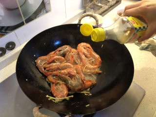 油焖大虾,倒入料酒翻炒均匀，再倒入适量清水。