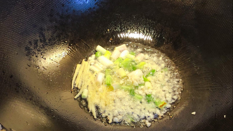 油焖大虾,锅内倒入适量油，温热后倒入葱白、蒜粒和姜丝爆香。