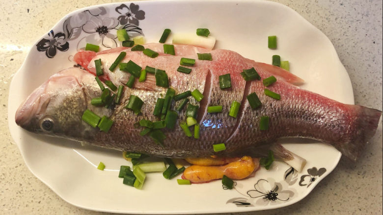 清蒸鲈鱼,把腌制好的鲈鱼的酒倒出，鱼放回盘子里，在盘子底上要刷上油，摆上鲈鱼（不要把酒倒进去），之后把一半的姜蒜和葱白放在鱼肚和鱼上。