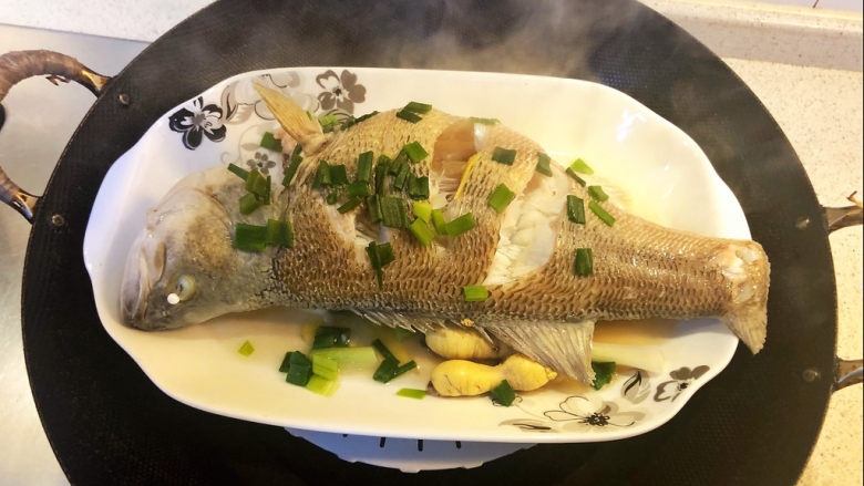 清蒸鲈鱼,蒸完鲈鱼之后把盘里的水和部分姜葱蒜倒掉。