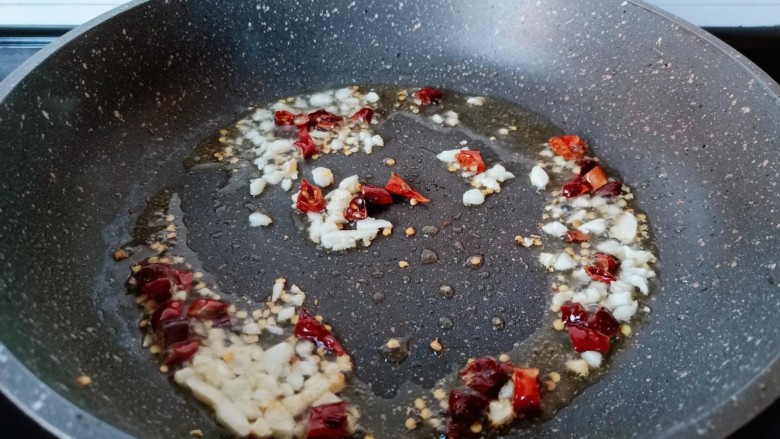 醋溜大白菜,锅里冷油下蒜末与干辣椒段炒香。