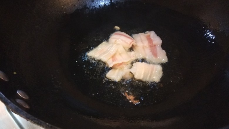 油菜炒虾仁,锅中倒入适量油烧热，放几片五花肉片。