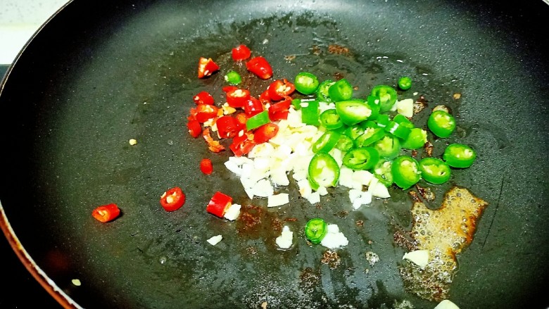 金针菇牛肉卷,锅中放入适量油，放入青、红尖椒和蒜末