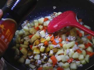 肉末烧土豆,倒入适量的红烧酱油，料酒，把食材炒上色。
