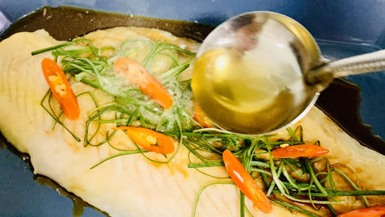 清蒸巴沙鱼柳,在浇洒热油淋在葱丝鱼肉上。