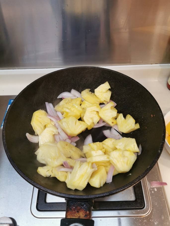 广式酸甜排骨,倒起锅内的油，放入洋葱、菠萝大火翻炒至熟，装上碟备用。