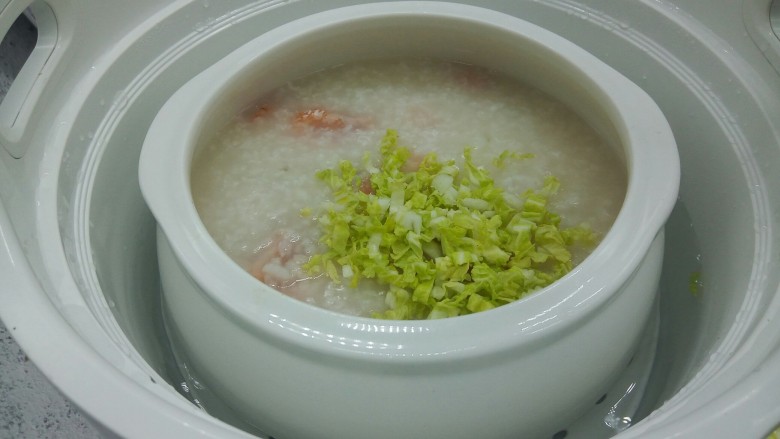 鲜虾砂锅粥,用筷子搅拌白菜丝。