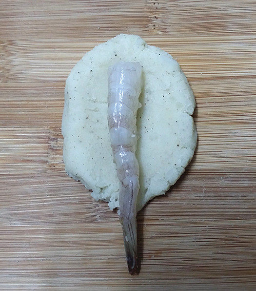 鲜虾饼,取适量土豆泥压扁，再把腌好的大虾放在上面包裹好，