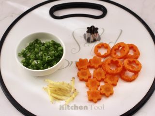 鲜虾砂锅粥,葱叶切碎，胡萝卜用模具刻成小花朵，姜切丝。