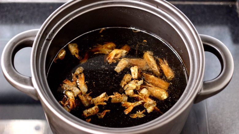 鲜虾砂锅粥,砂锅里倒入适量的清水，放入榨好的虾壳和虾头。