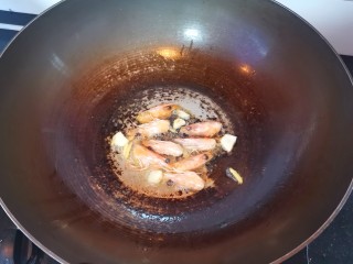 鲜虾砂锅粥,另起锅倒入油，放入姜丝蒜片爆香，倒入虾头炒出虾油