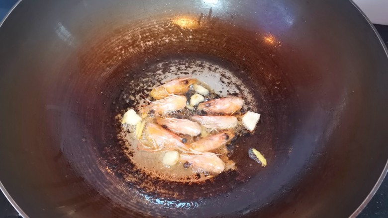 鲜虾砂锅粥,另起锅倒入油，放入姜丝蒜片爆香，倒入虾头炒出虾油