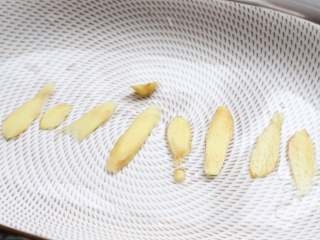 清香蒸鲈鱼,取一个长盘子，盘子底部铺上姜片。