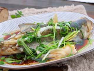 清香蒸鲈鱼,锅中倒入一勺油，油温烧至八成热，趁热浇在鱼身上即可上桌。