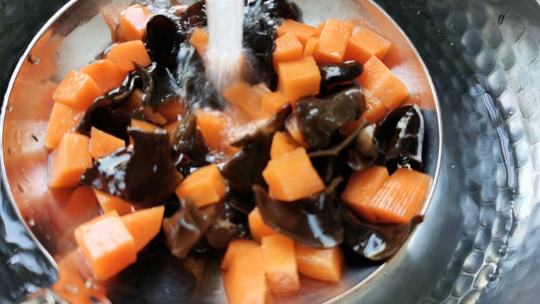 黄瓜木耳炒虾仁,将胡萝卜和木耳放入沸水中焯水几秒钟，捞出用冷水冲一下，控水备用。