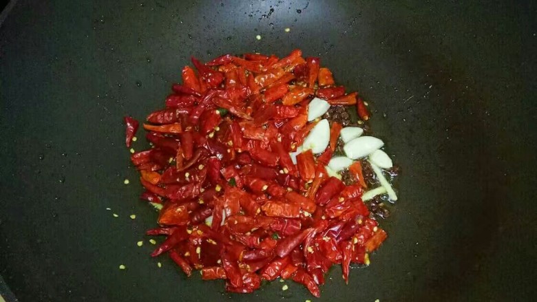 麻辣干锅鸡,放入干红辣椒，蒜瓣，翻炒至呛鼻