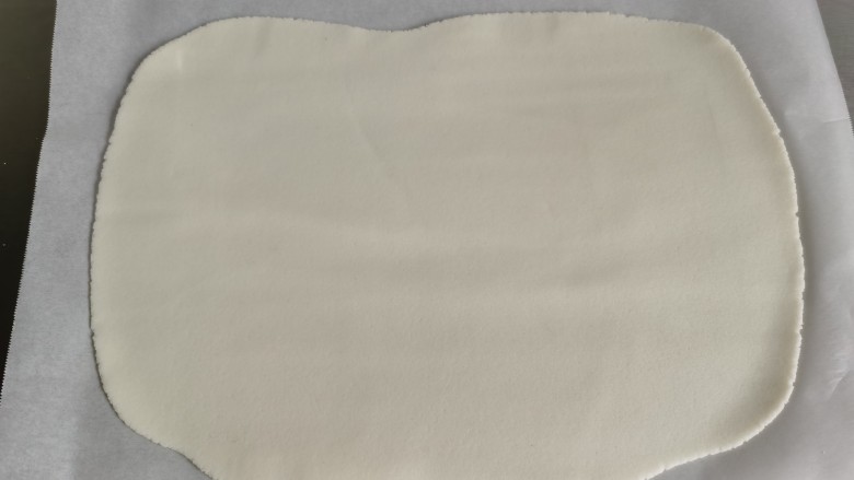 红糖麻糍,为了防沾，可在面板上铺一张油纸，放入粉团擀成薄片。