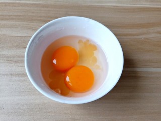 鸡蛋西红柿打卤面,碗里嗑入两个鸡蛋，加半勺料酒打散。